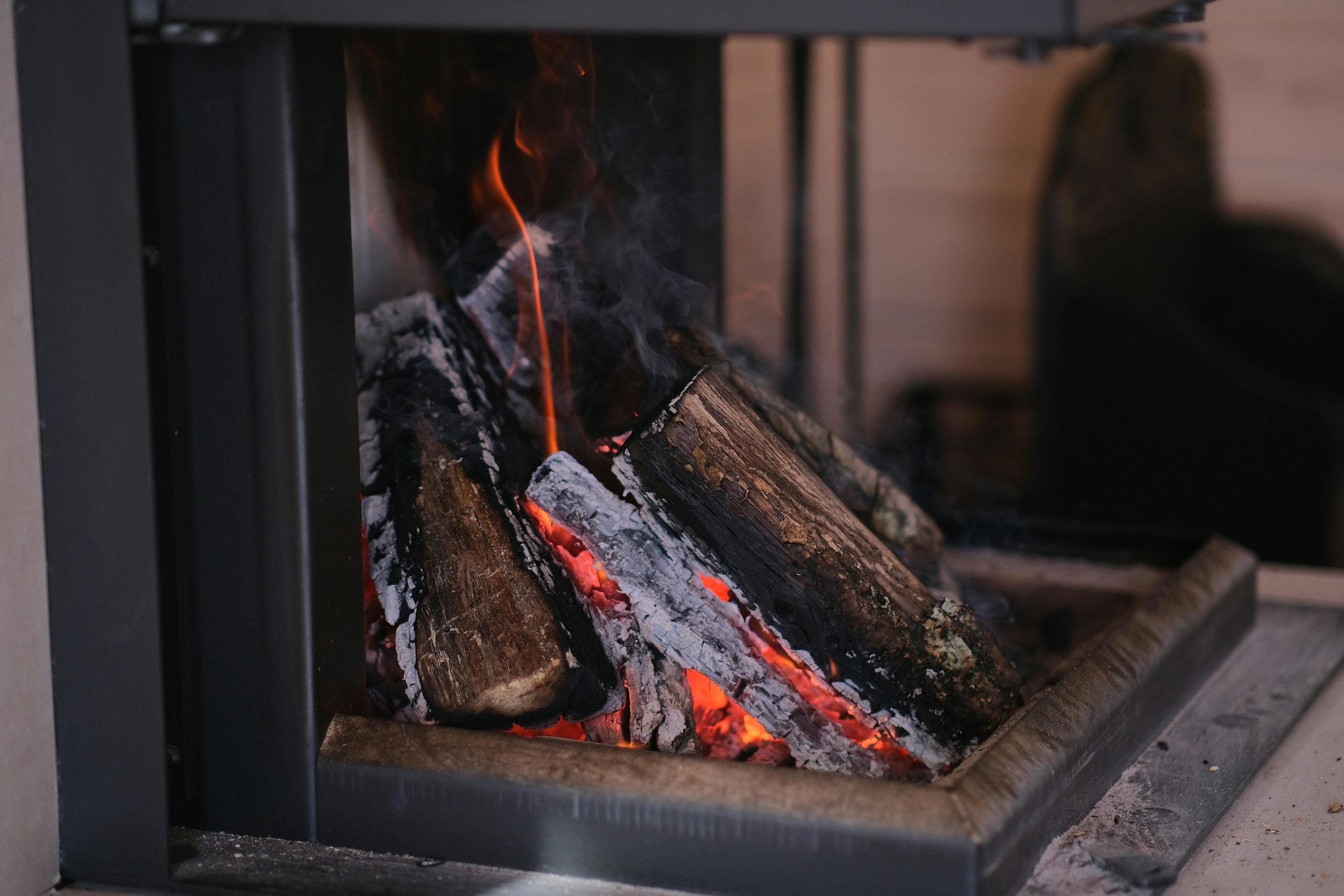 Firewood burning in a fireplace, producing wood ash for garden use